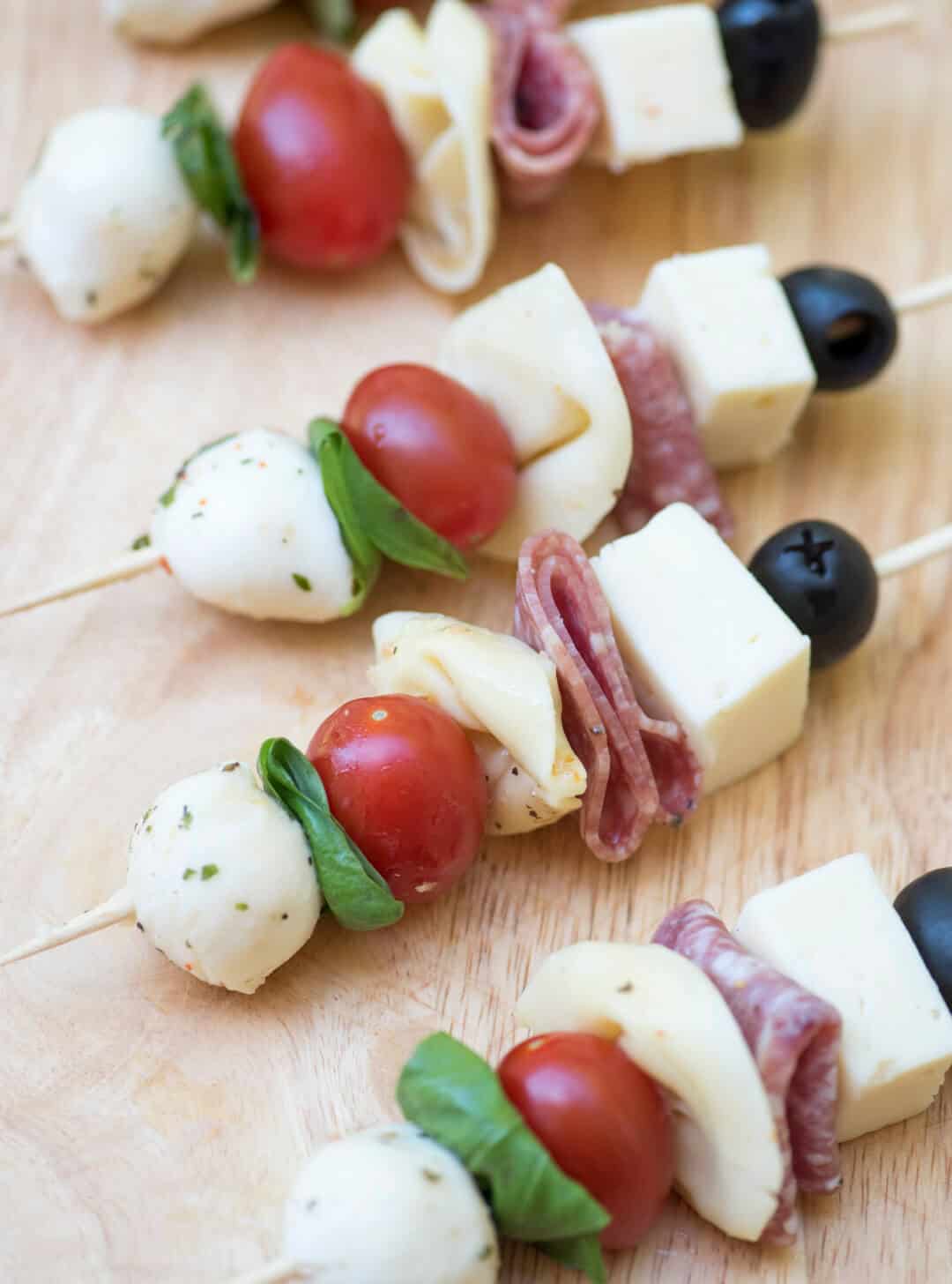 Four assembled antipasto skewers on a cutting board.