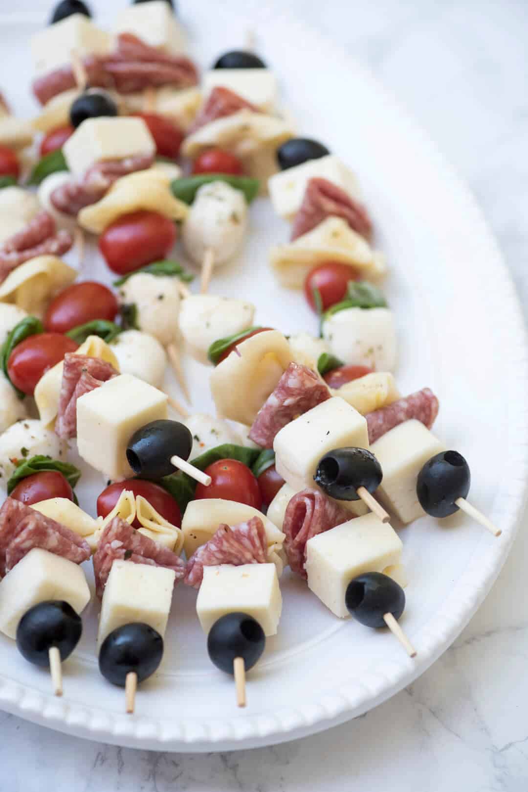 A white platter filled with the antipasto skewers.