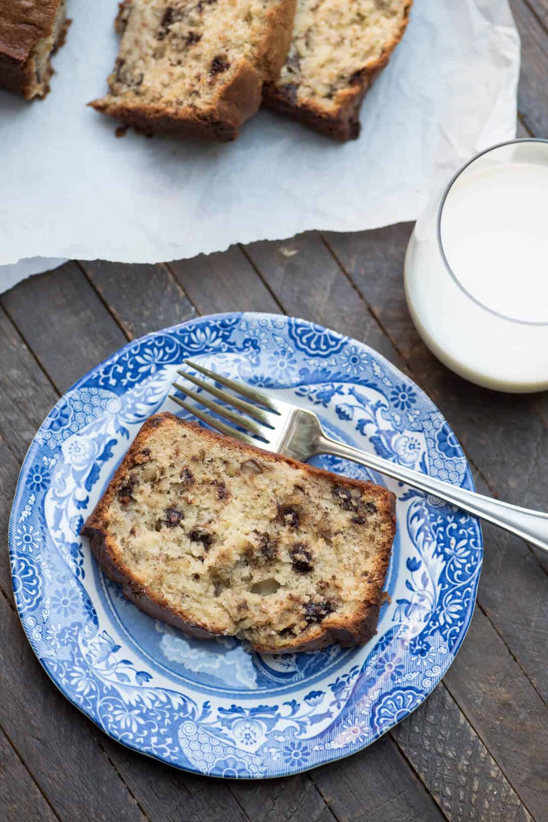 A slice of Sour Cream Chocolate Chip Banana Bread on a blue plate with a fork.