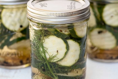 A mason jar filled with zucchini pickles and fresh dill.