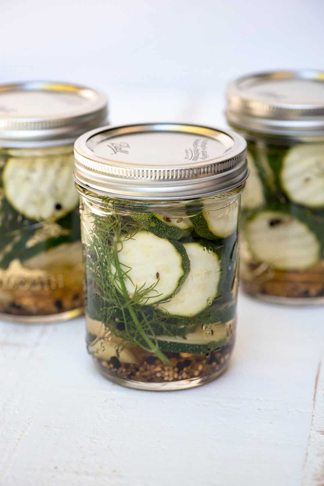 Three mason jars full of Refrigerator Zucchini pickles.
