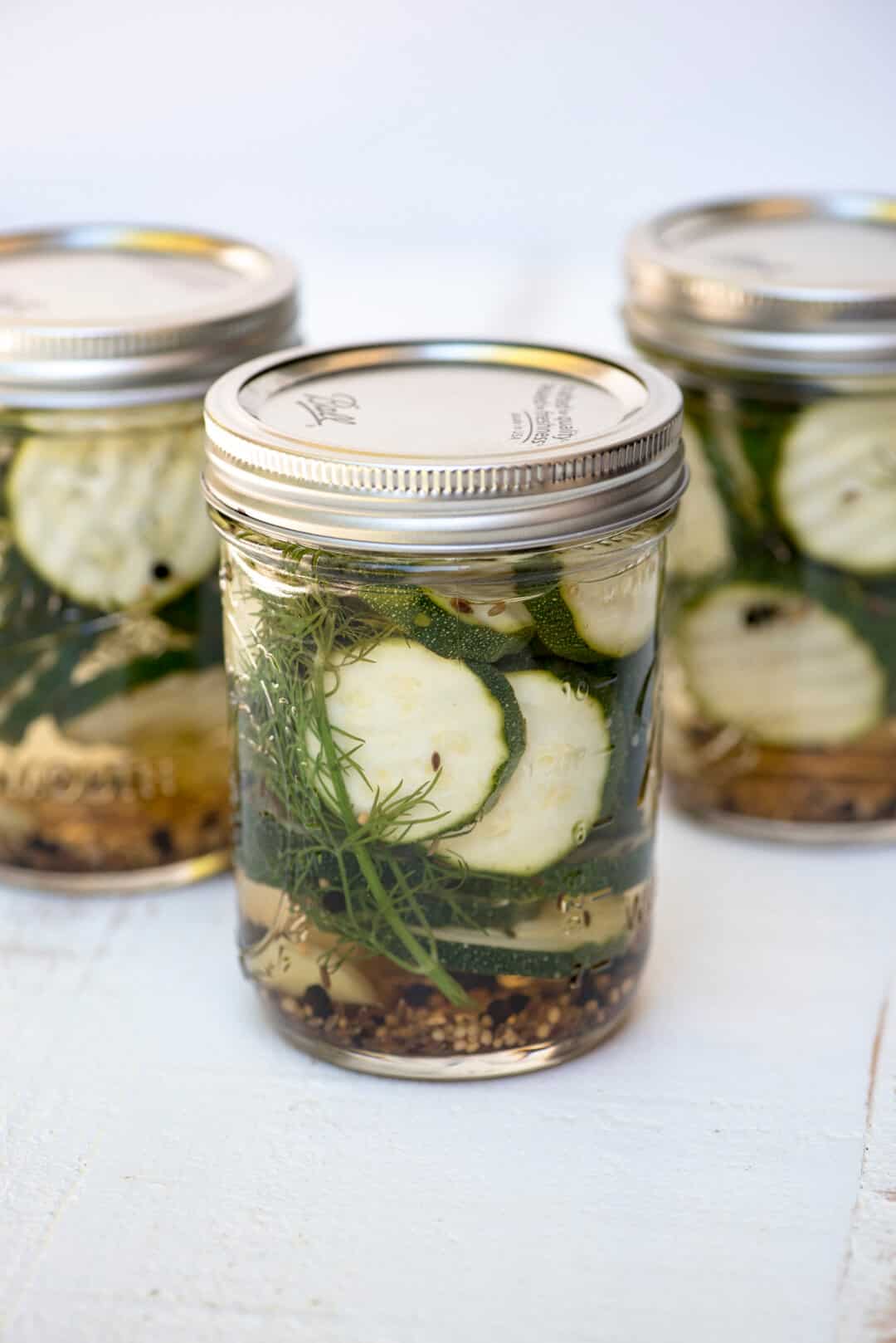 A mason jar filled with zucchini pickles and fresh dill.