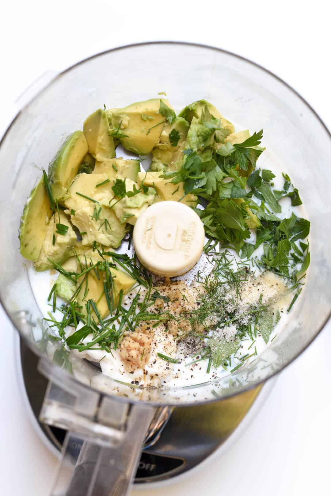 The ingredients for Avocado Ranch Dressing in the bowl of a food processor.