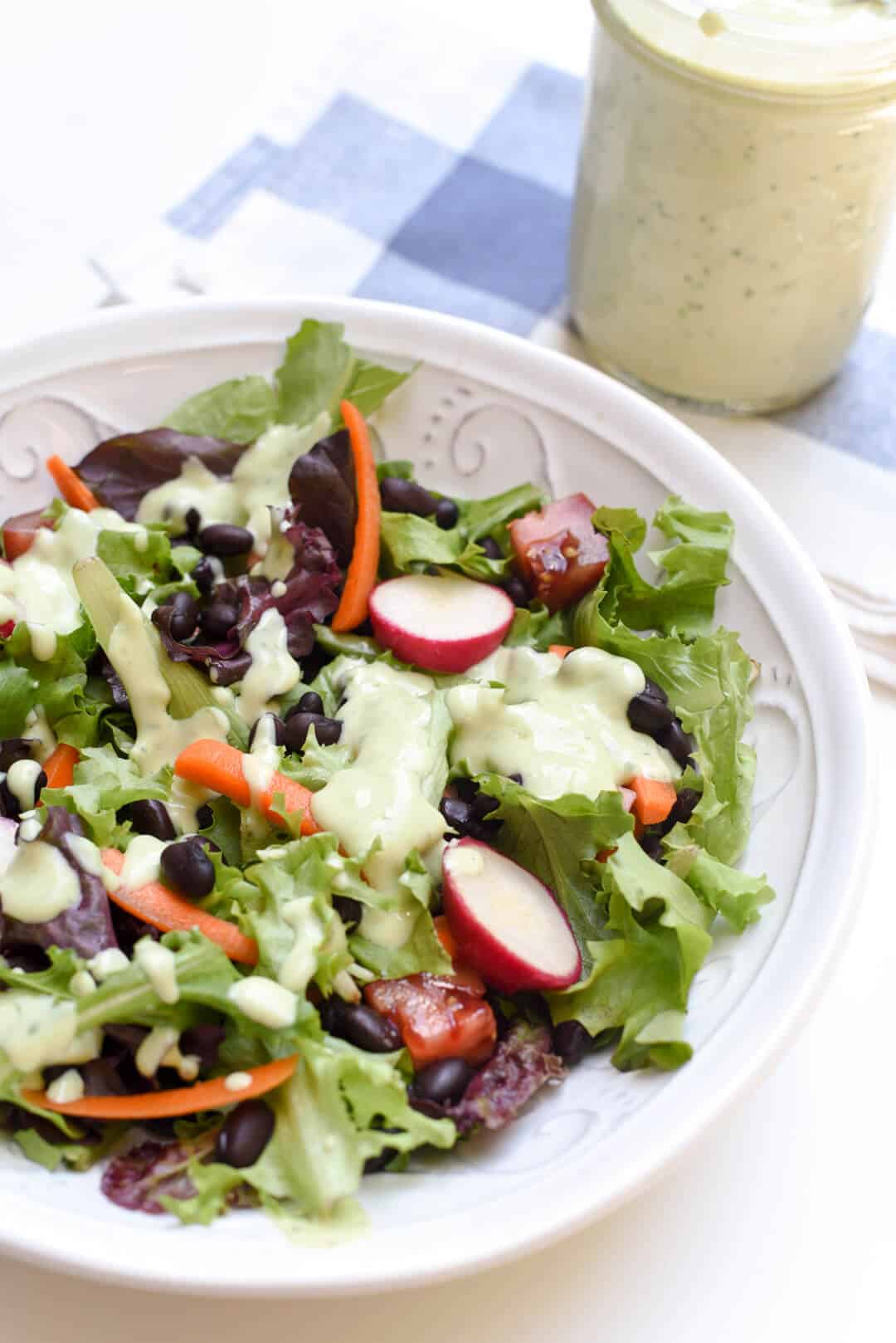 A green salad in a white bowl dressed with Avocado Ranch Dressing.