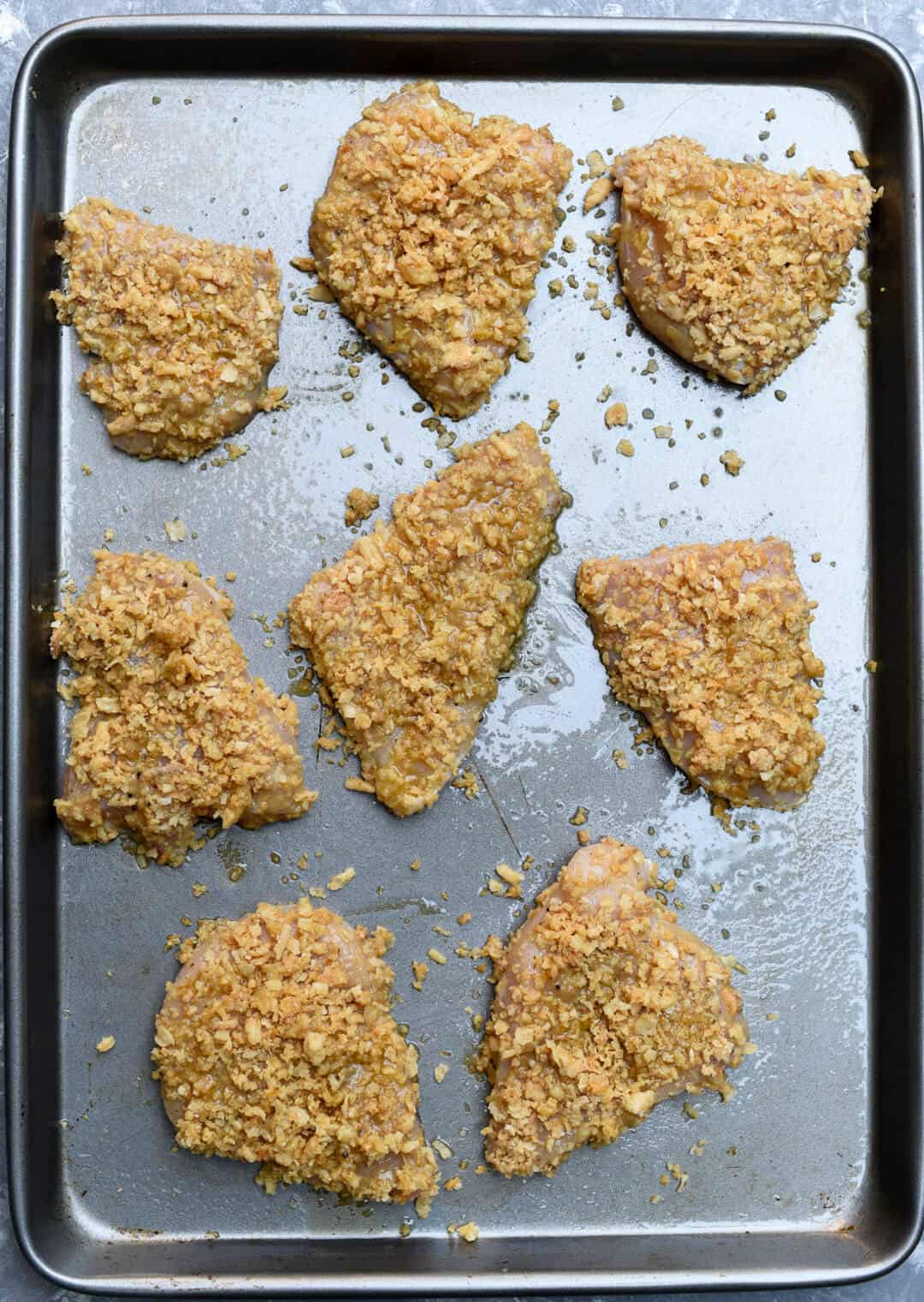 Breaded chicken on a baking sheet.