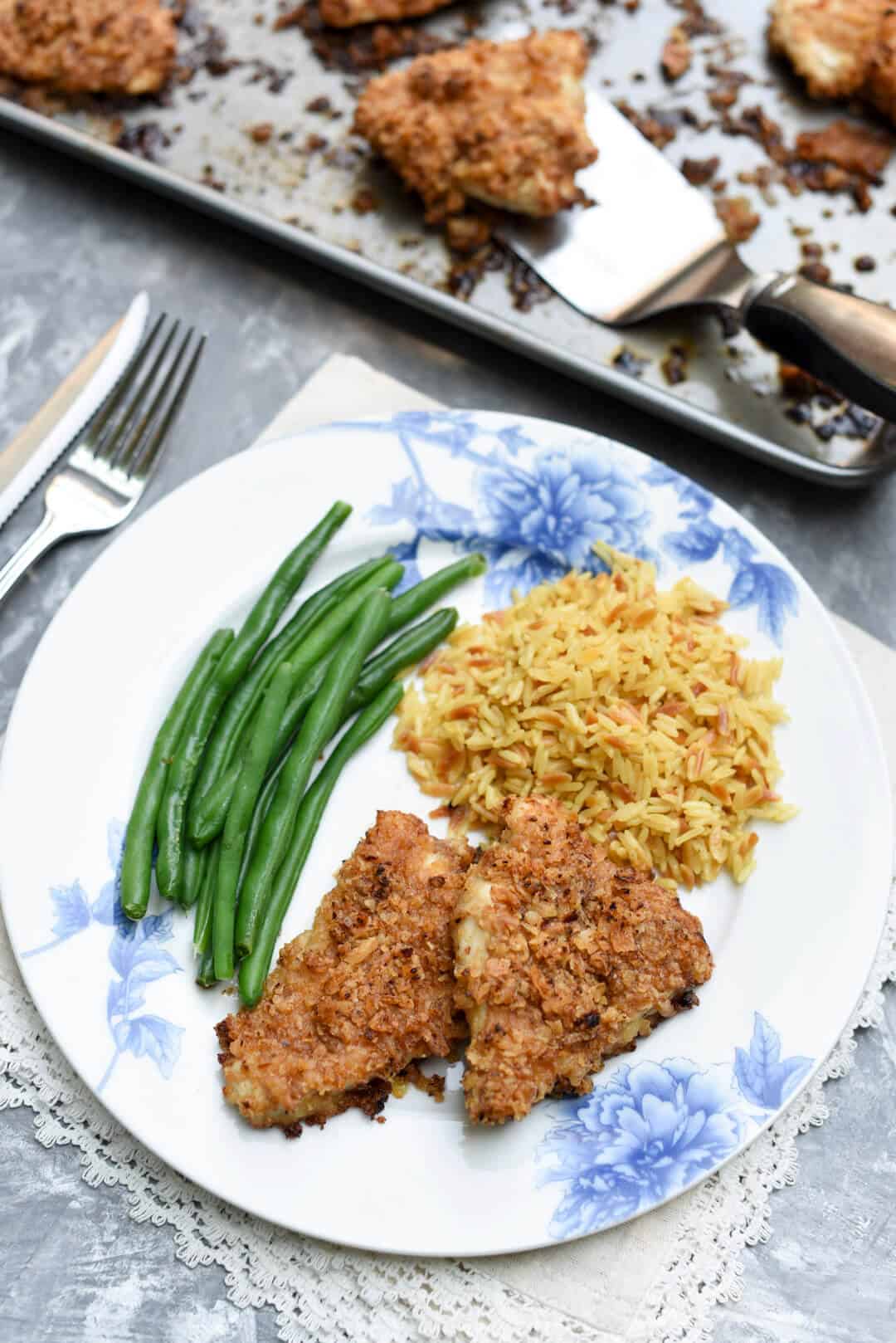 Crispy Onion Chicken on a plate with green beans and rice.