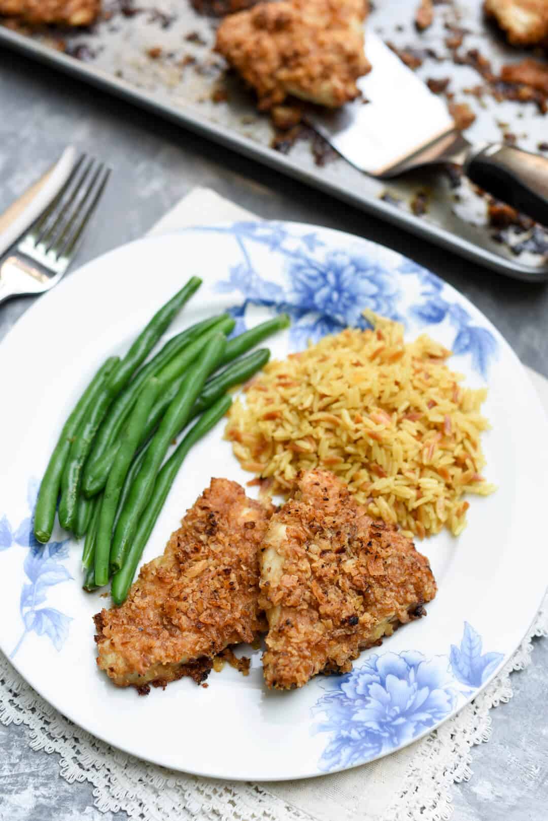 Crispy breaded chicken on a plate with green beans and rice.