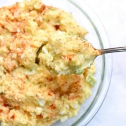 A spoon lifts Potato Salad from a bowl.