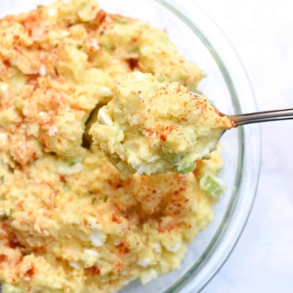 A spoon lifts Potato Salad from a bowl.