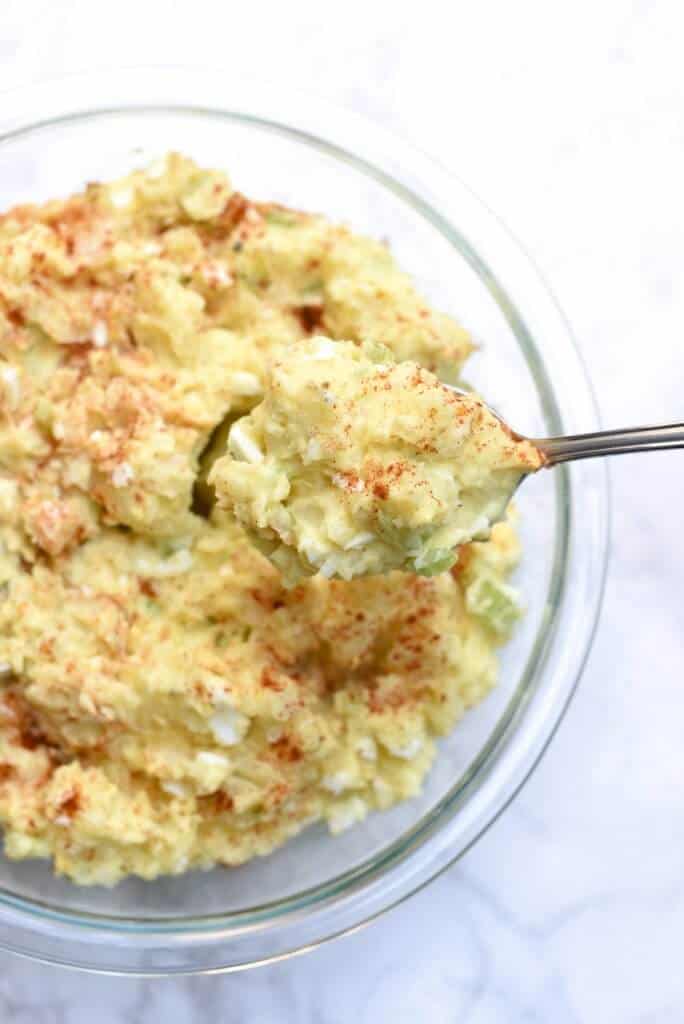 A spoon lifts Potato Salad from a bowl.