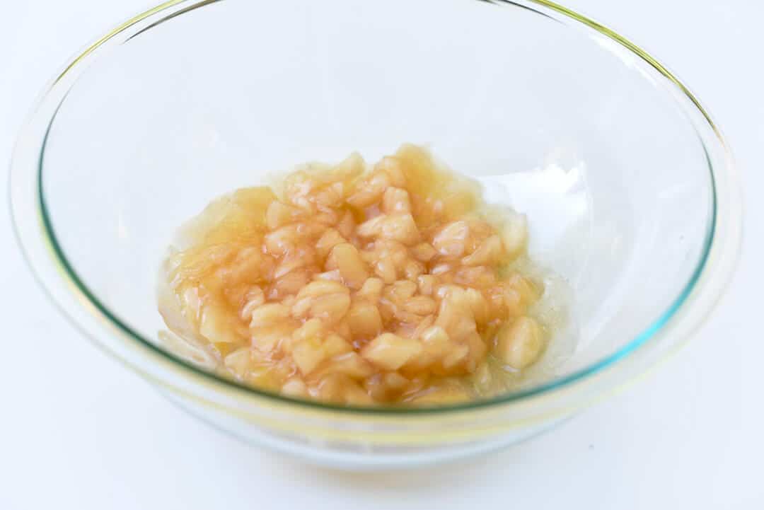 Canned apple pie filling in a clear glass mixing bowl.