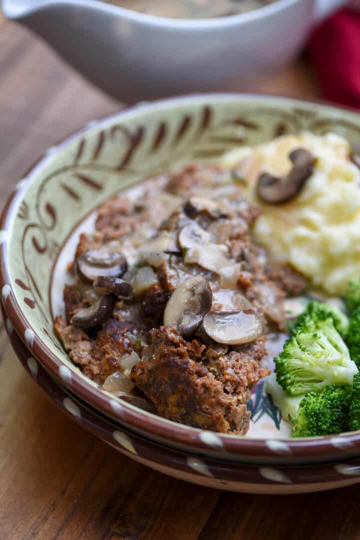 A serving of the meatloaf with broccoli and mashed potatoes in a bowl.