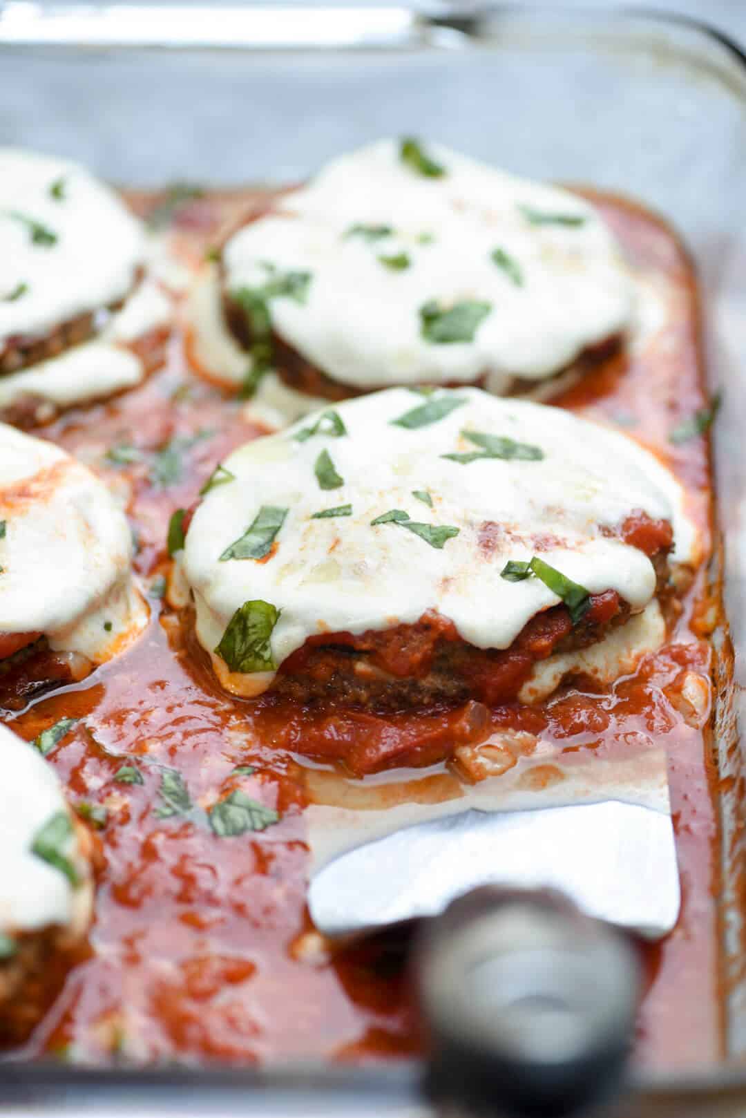 A close up image of Baked Eggplant Parmesan in a baking dish.
