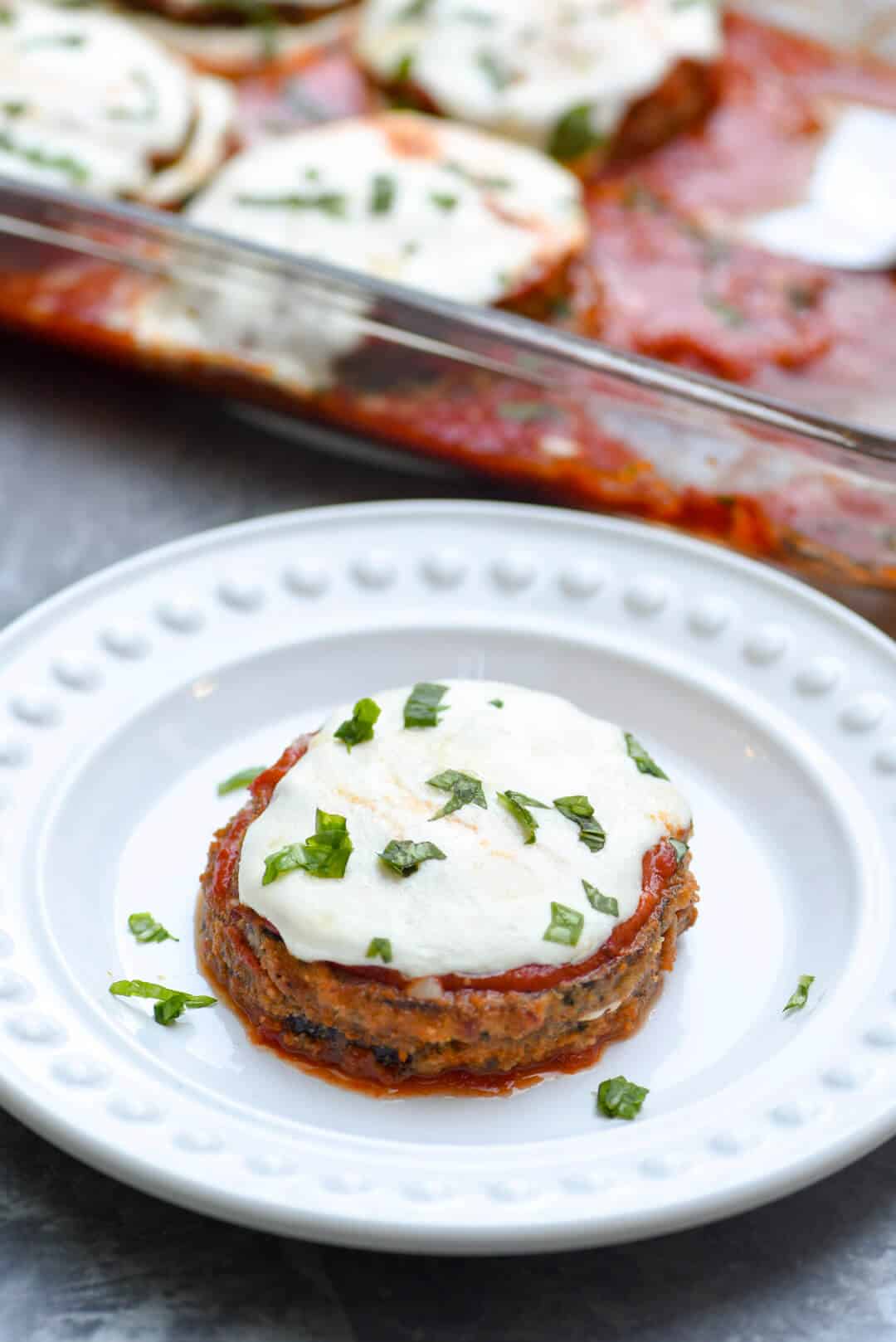 A serving of eggplant parmesan on a white plate.