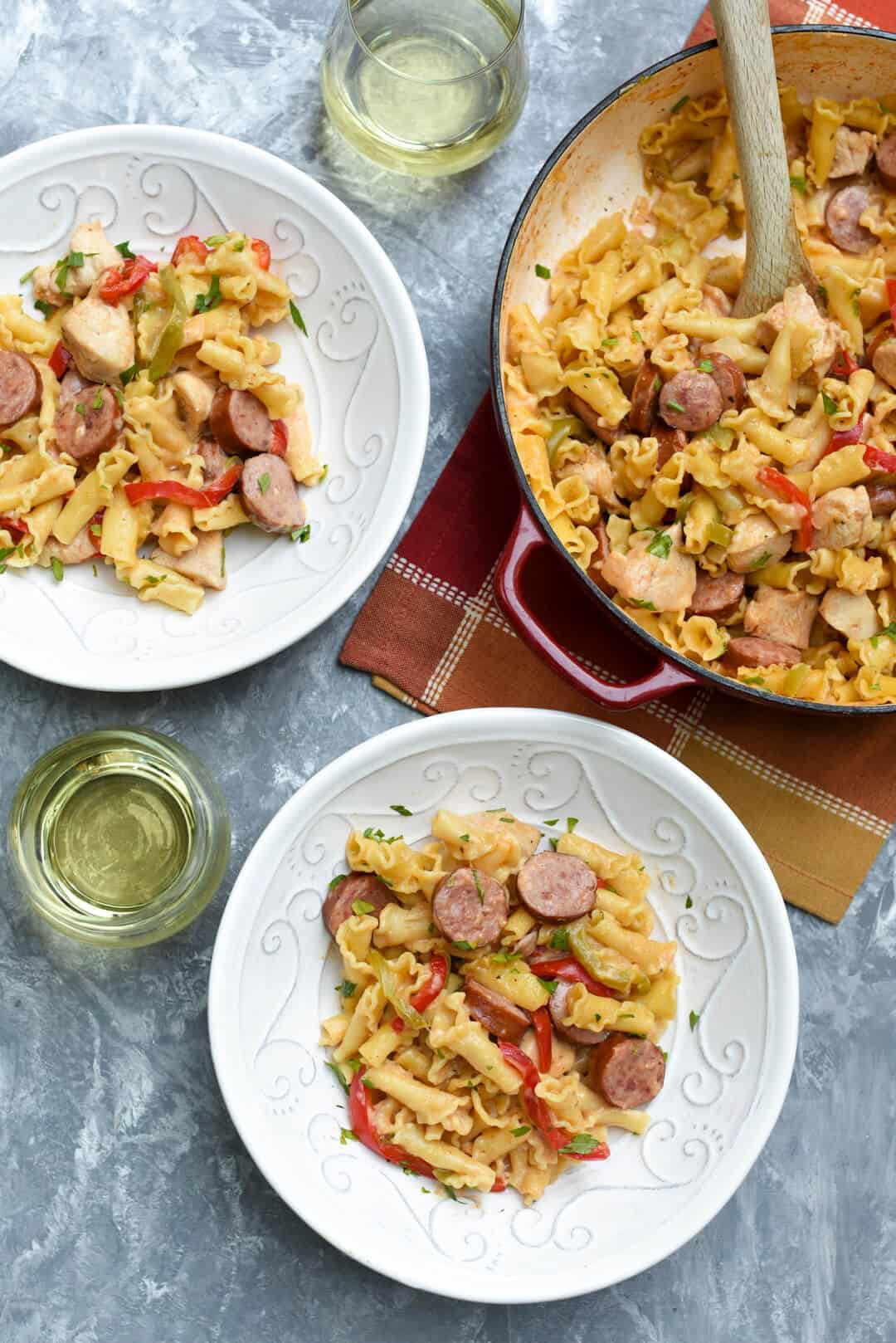 Two bowls filled with pasta with a skillet behind.