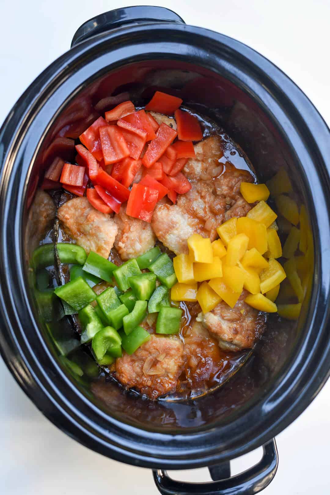 Colorful bell peppers are added to the slow cooker.
