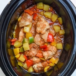 A slow cooker filled with sweet and sour chicken shot from over the top.
