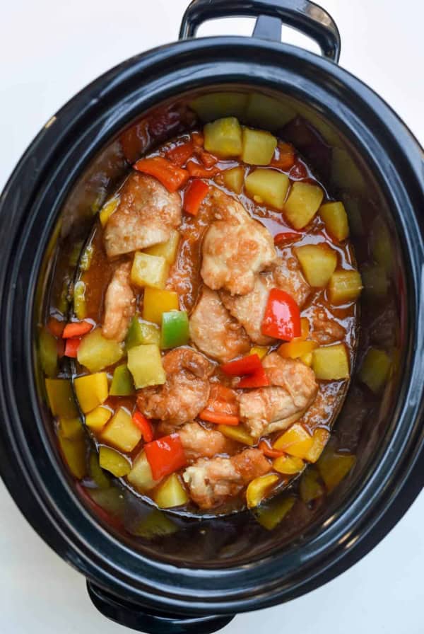 A slow cooker filled with sweet and sour chicken shot from over the top.