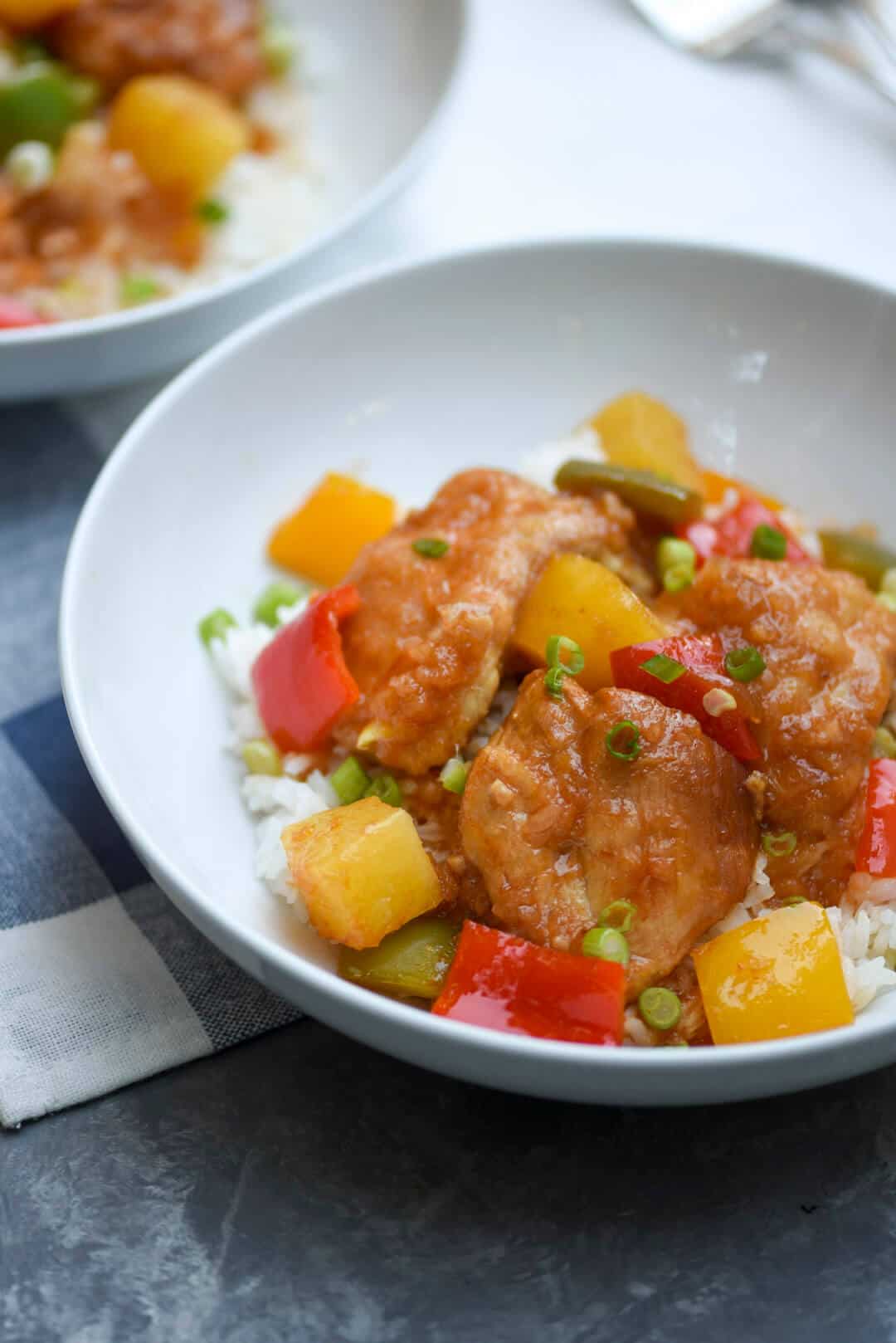 A serving of the sweet and sour chicken in a white bowl over rice.