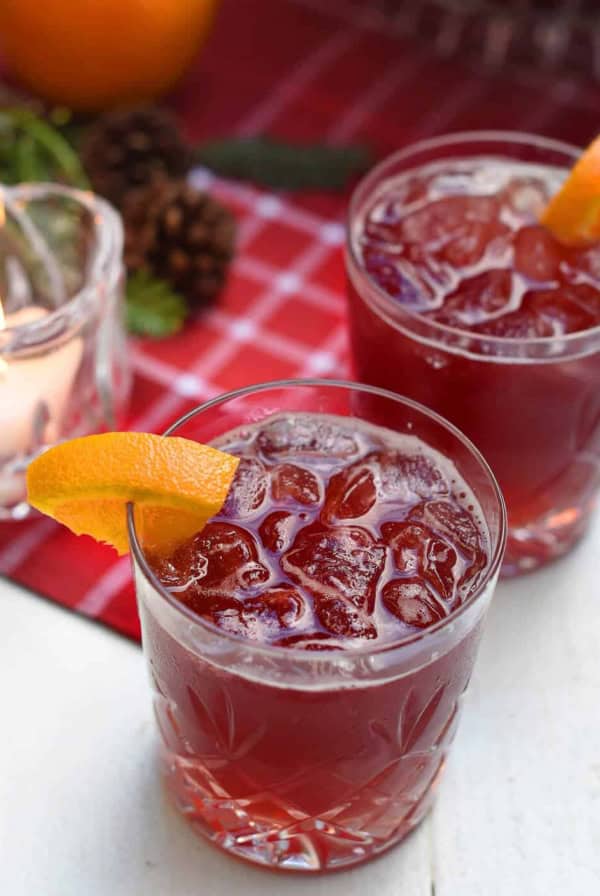 A close up of a red beverage with a slice of orange.