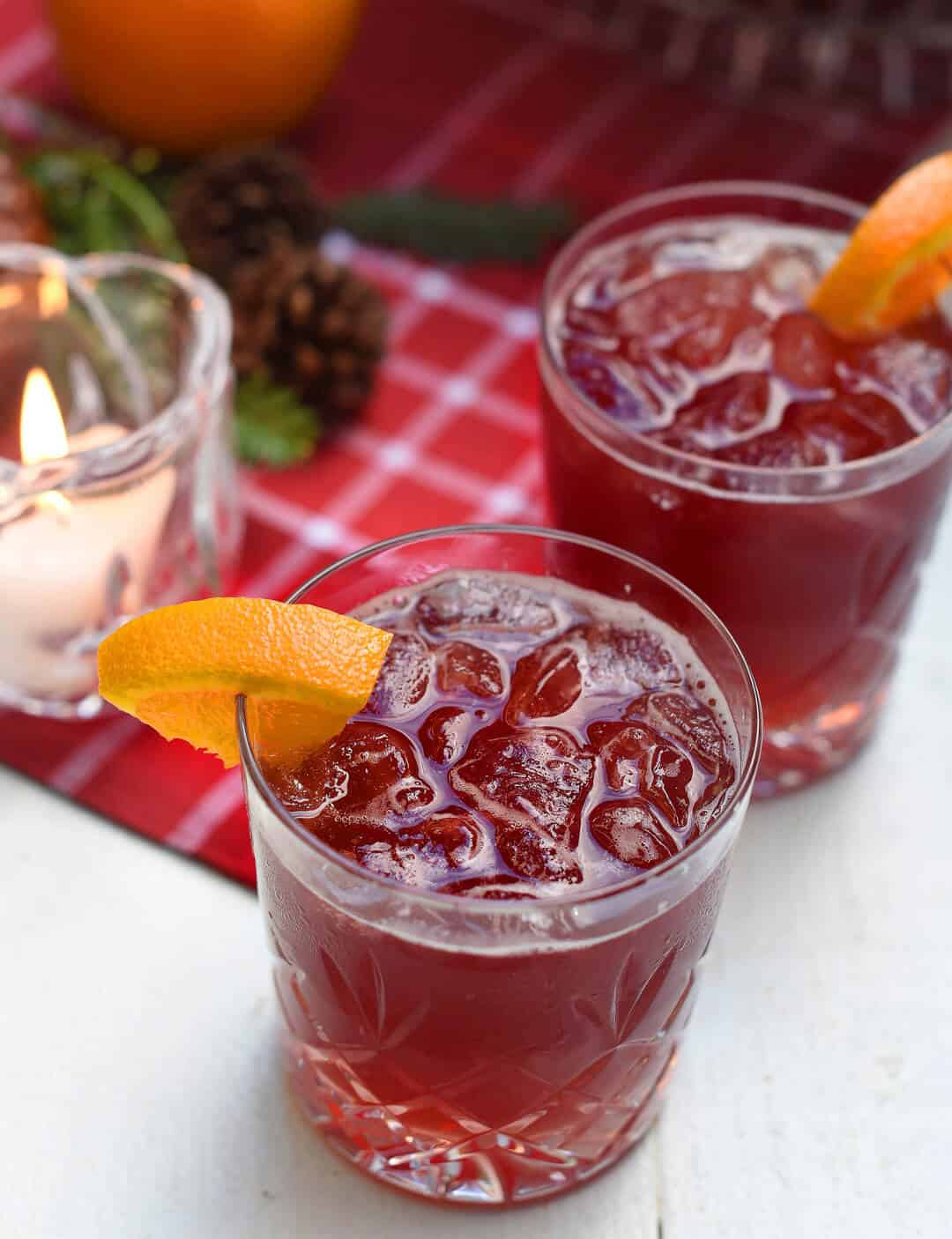 A close up of a red beverage with a slice of orange.