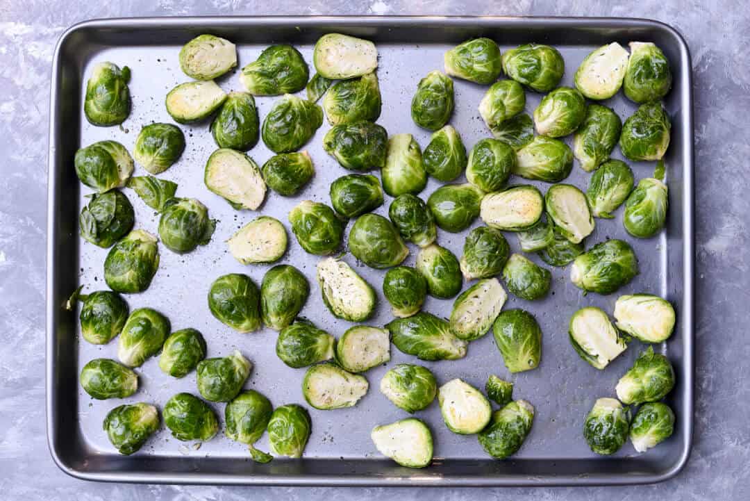Halved Brussels sprouts on a rimmed baking sheet.