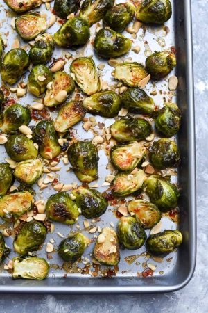 A baking sheet filled with glazed brussels sprouts and peanuts.