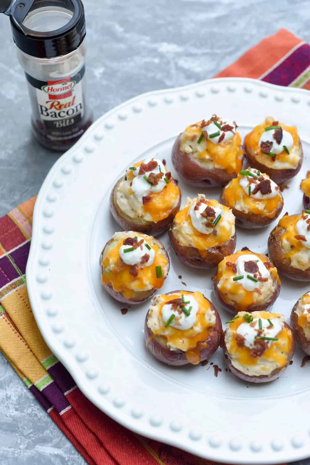 Fully Loaded Twice Baked Potato Bites on a white serving platter with Hormel Bacon Bits in the background.