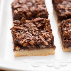 A white platter filled with Chocolate Bourbon Pecan Pie Bars.