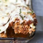 A spatula lifts a lasagna rollup from a baking dish.