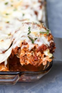 A spatula lifts a lasagna rollup from a baking dish.