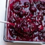Cranberry sauce in a glass dish with spoon.