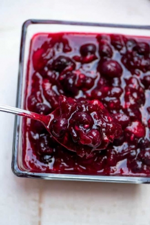Cranberry sauce in a glass dish with spoon.