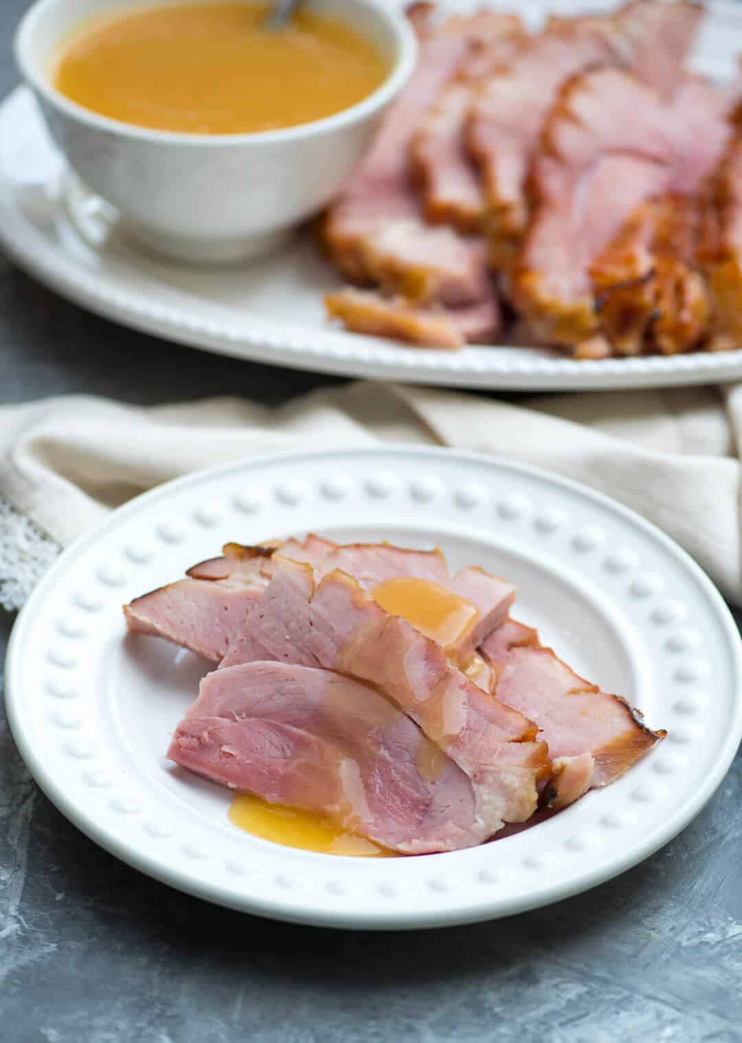 A serving of ham on a white plate with pineapple sauce drizzled over the top.