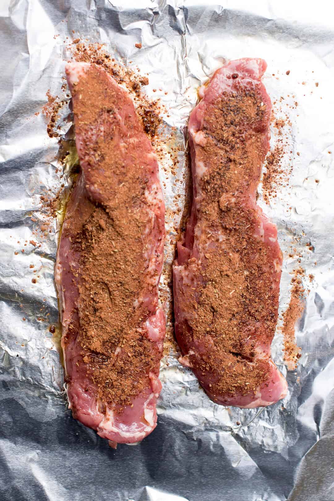 An in process image showing two tenderloins coated with the spice mixture.