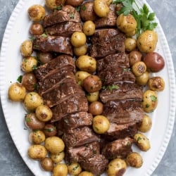 A platter with slices of pork tenderloin and potatoes.