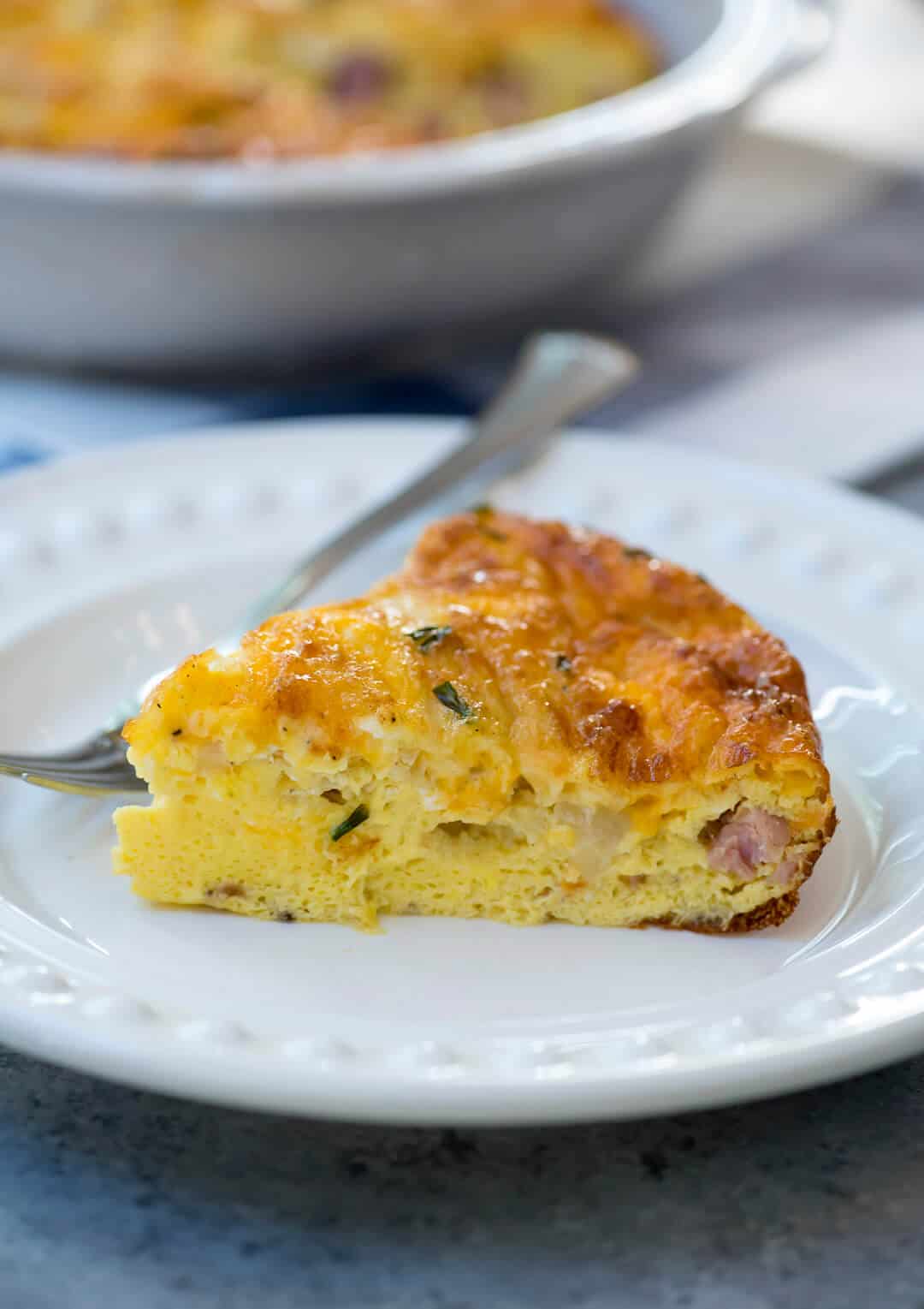 A slice of Ham and Cheese Crustless Quiche on a plate with a fork.