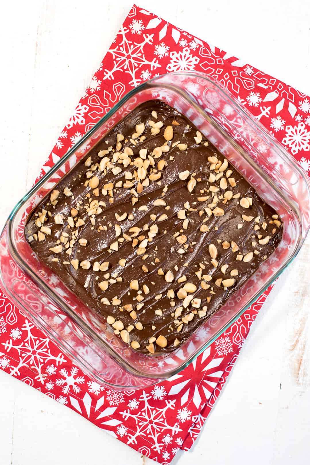 The fudge in a glass baking dish on top of a red cloth shot from over the top.