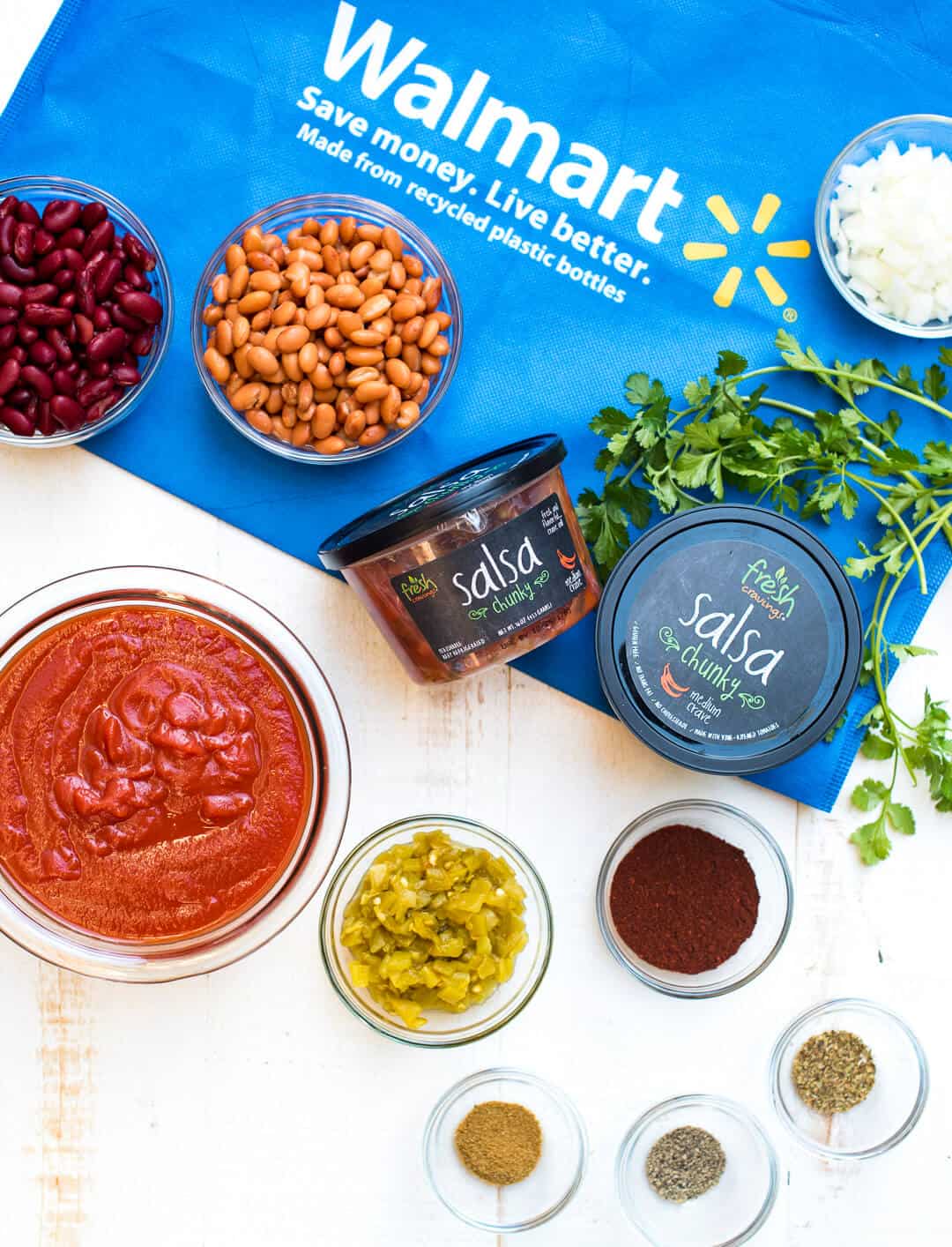 The ingredients for Slow Cooker Salsa Chili including Fresh Cravings Salsa on a blue Walmart shopping bag.