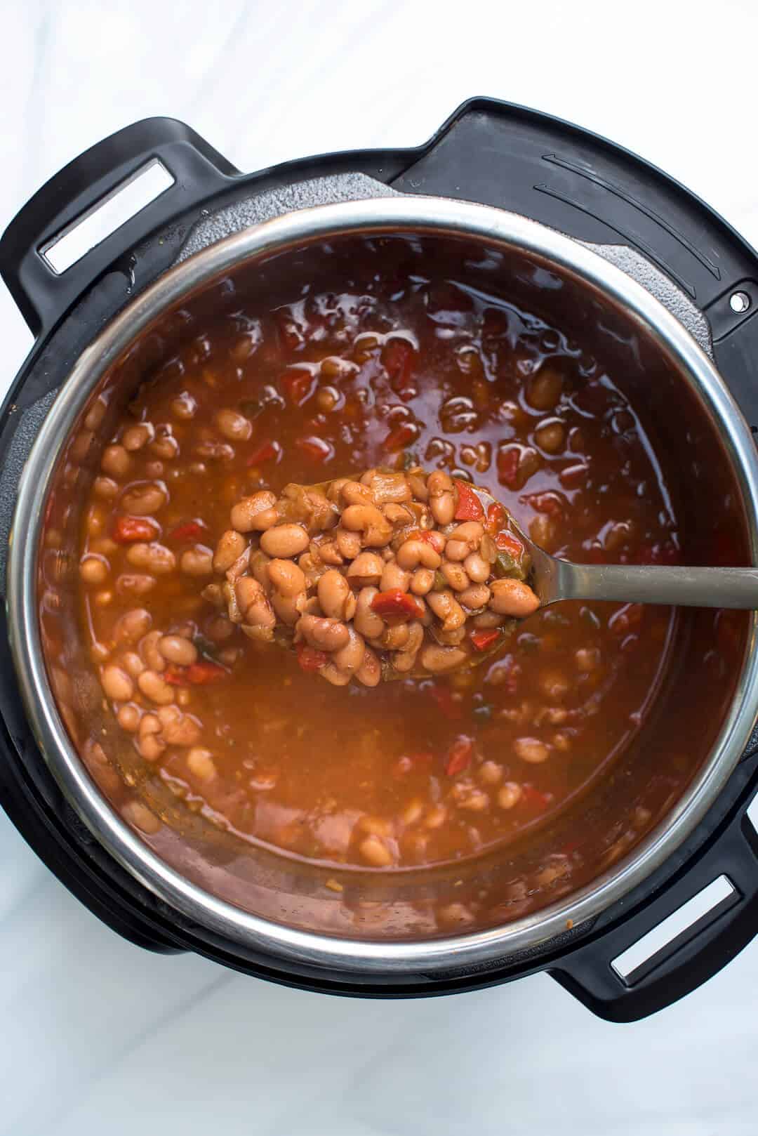  An over the top image showing a spoon lifting some of the Mexican Pinto Beans from the Instant Pot.