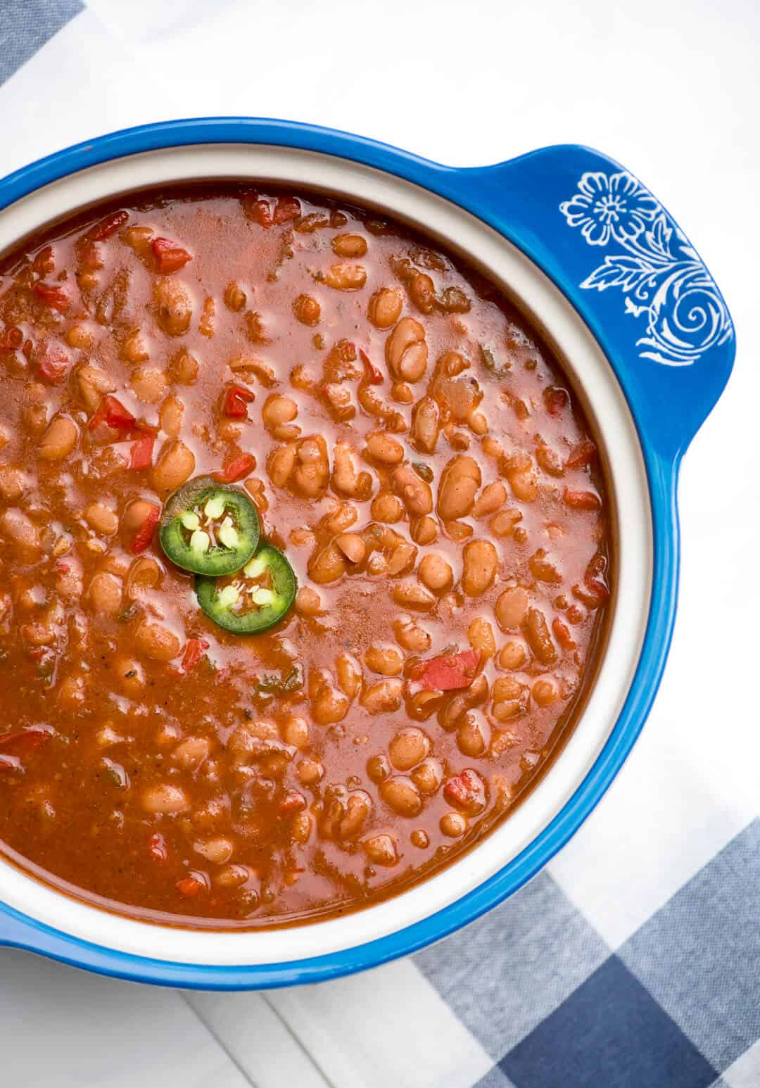 An over the top image showing Instant Pot Mexican Pinto Beans in a pretty blue serving dish with slices of jalapeno on the top.
