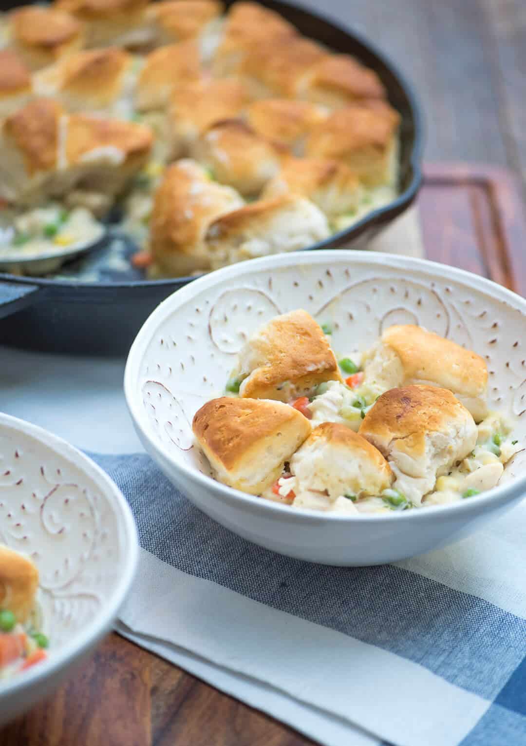 A serving of pot pie with biscuit topping in a white bowl.