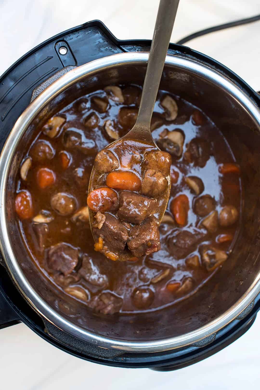 A serving spoon lifts some of the beef burgundy from the Instant Pot.
