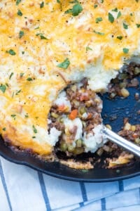 A spoon scoops up Shepherd's Pie from a skillet.