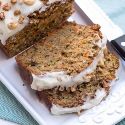 Slices of frosted Carrot Zucchini Bread on a white platter.