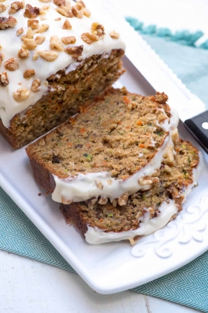 Slices of frosted Carrot Zucchini Bread on a white platter.