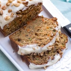 A sliced loaf of frosted Carrot Zucchini Bread on a white platter.