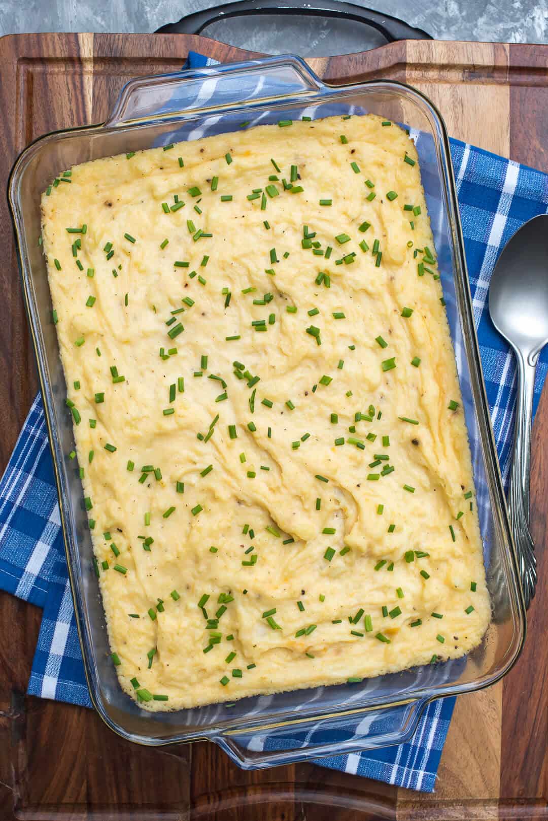 Mashed potatoes topped with chives in a 13-inch x 9-inch baking dish.