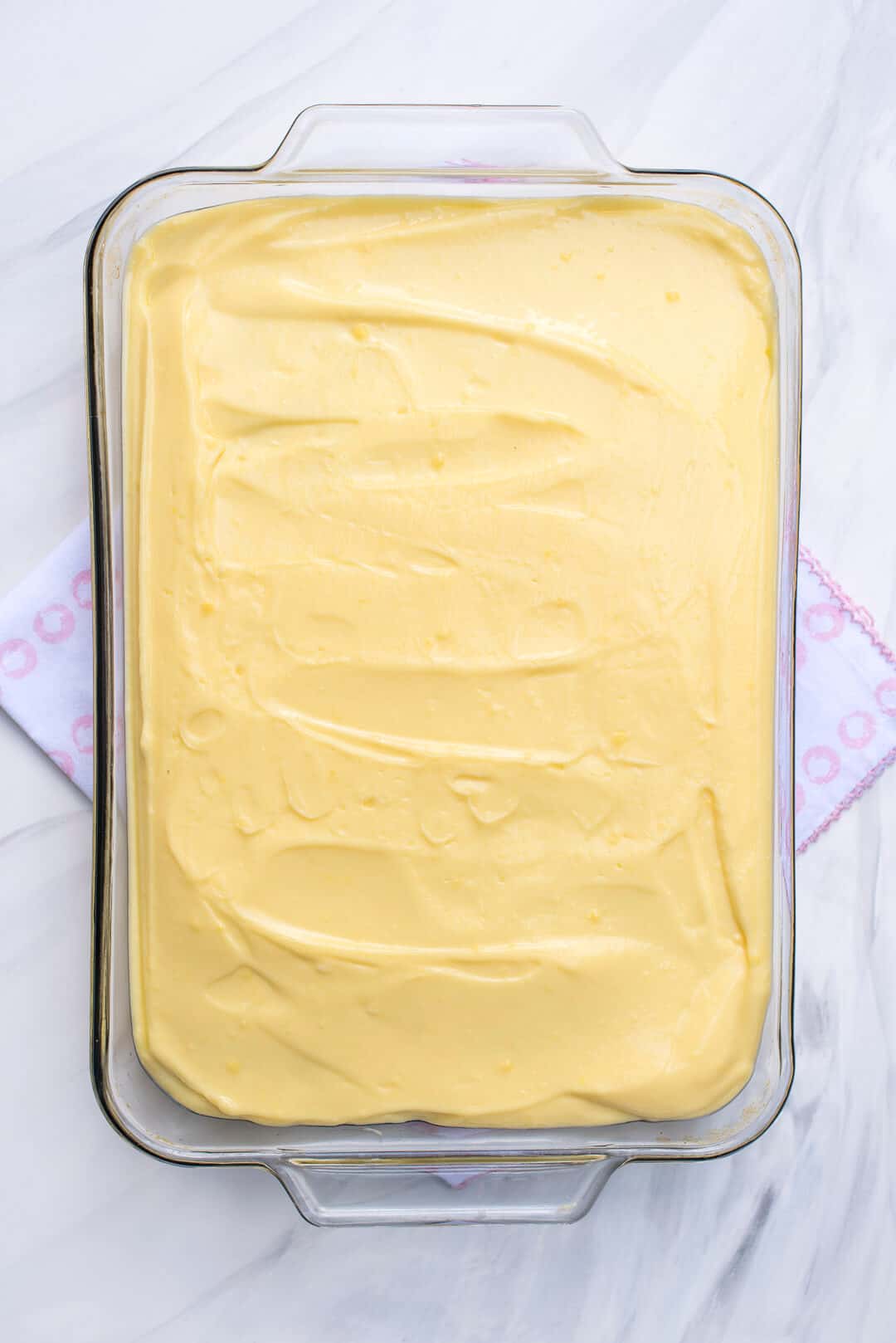 An in process image showing the coconut pudding layer spread into the baking dish.