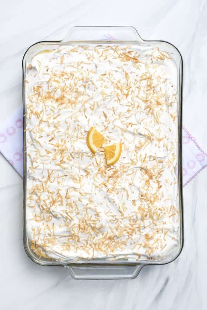 An over the top image of the frosted cake topped with toasted coconut and slices of fresh lemon.